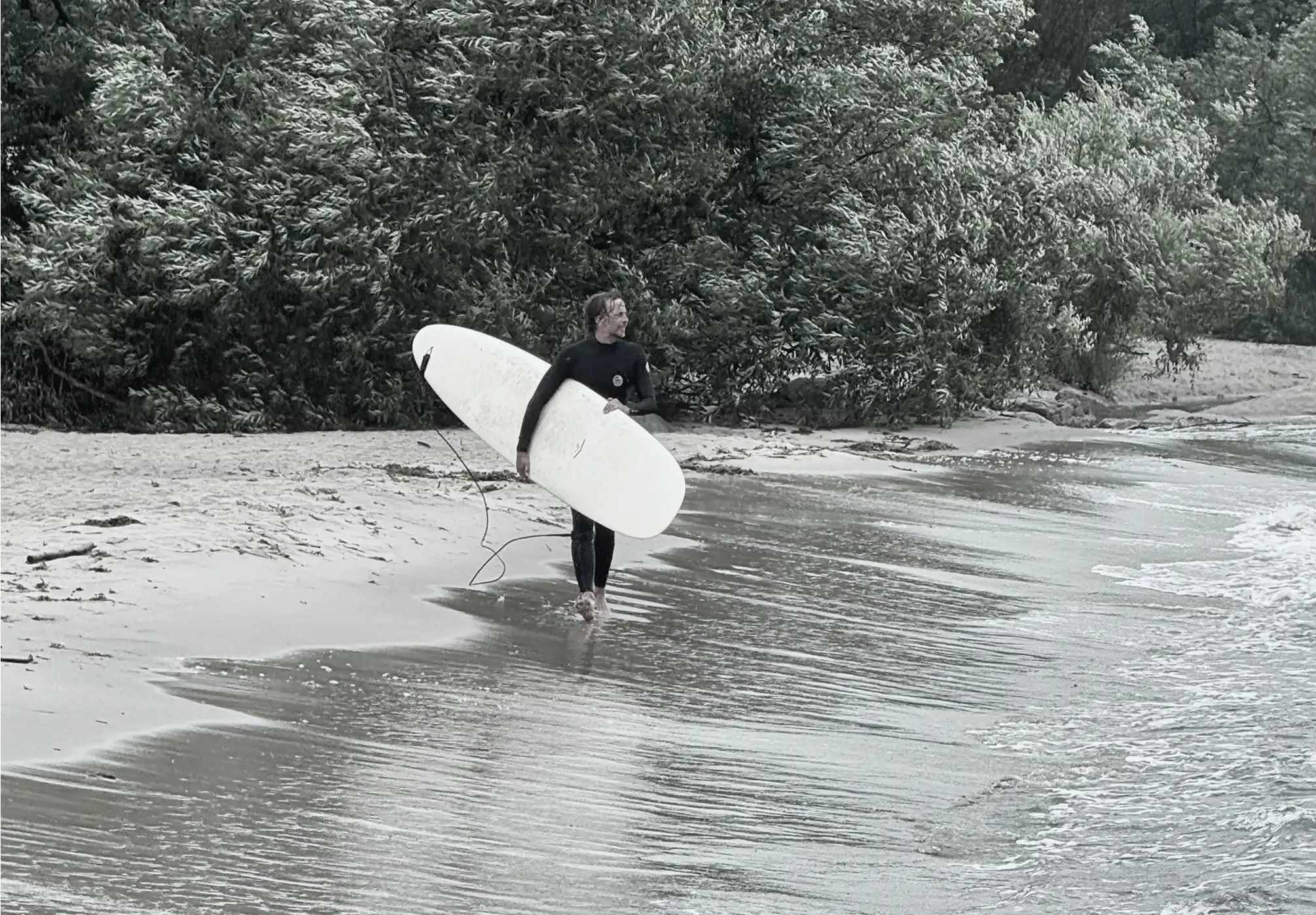 Johan bär en longboard längs stranden